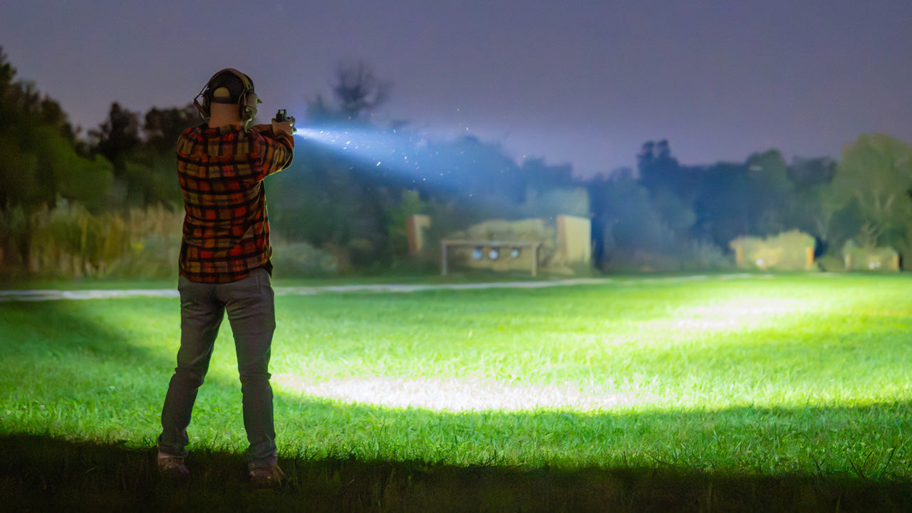 A very short man with a pistol using a weapon light to aim