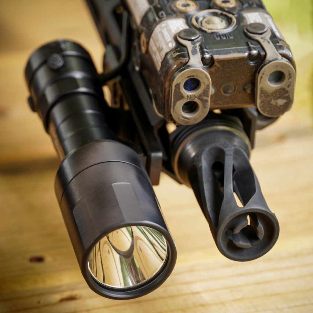 Close up of Rein micro flashlight on the end of a rifle.