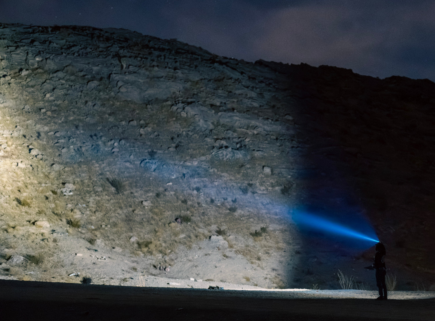 Man in desert shinning flashlight on a mountain