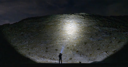 Man in desert shinning flashlight on a mountain