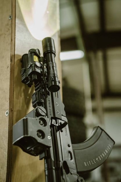 black rifle with black Rein flashlight leaning on a door frame.