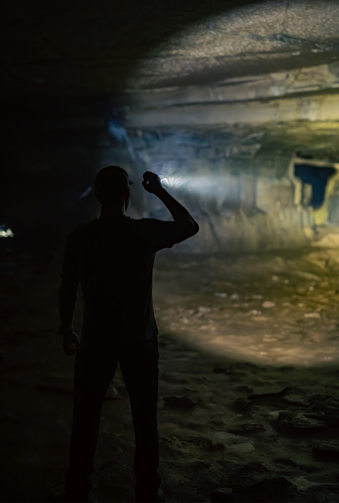 Man shining MCH Duty flashlight into a cave from behind