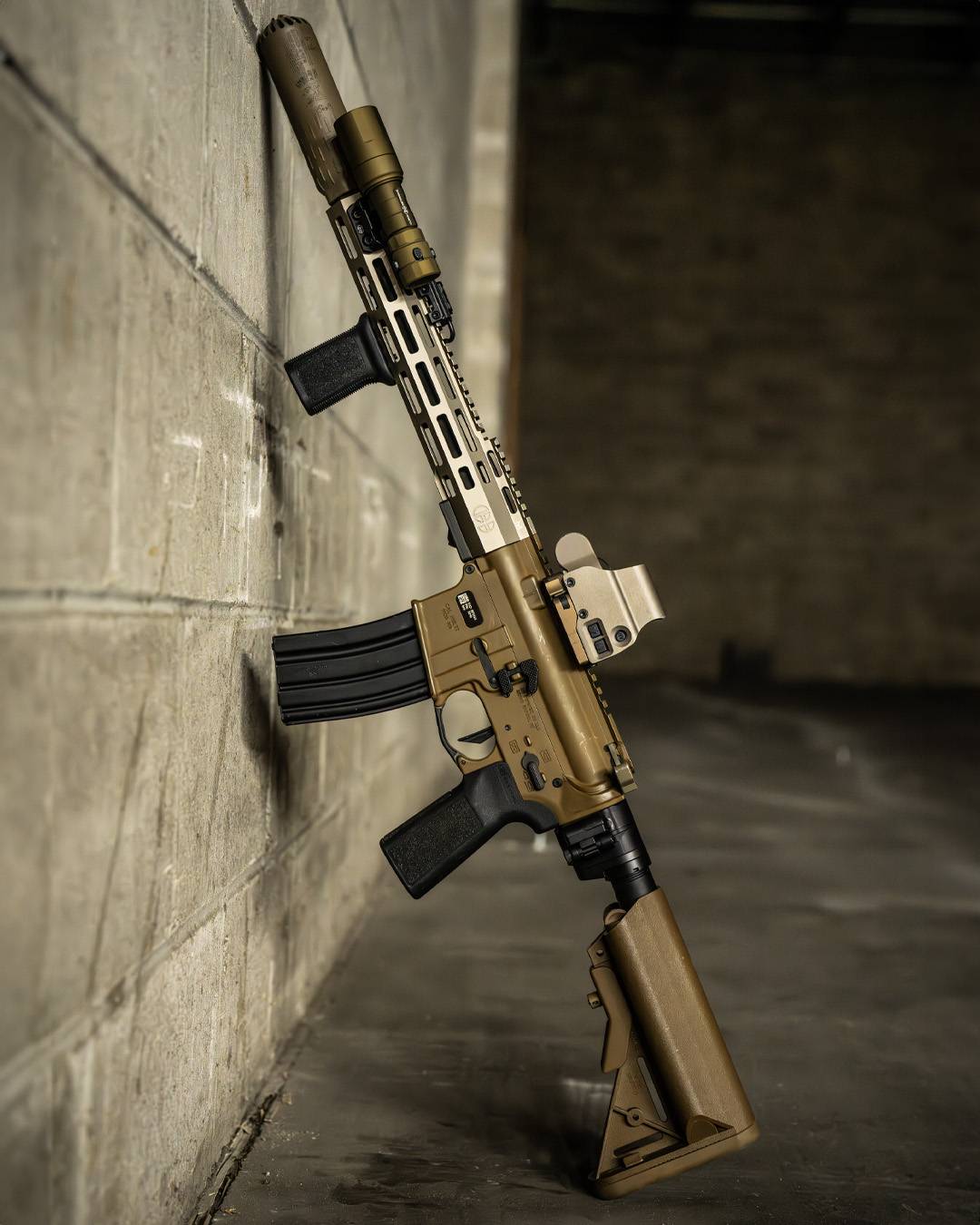 Tan rifle with FDE Rein Micro flashlight leaning against a wall.